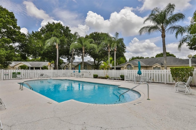 community pool with a patio and fence