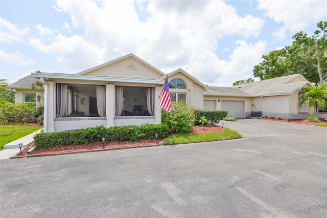 ranch-style house featuring an attached garage, stucco siding, concrete driveway, and central AC