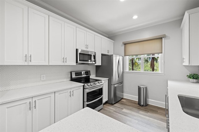 5000 Culbreath Key Way Unit 8-319, Tampa, FL 33611 - kitchen featuring appliances with stainless steel finishes, baseboards, crown molding, white cabinetry, and tasteful backsplash