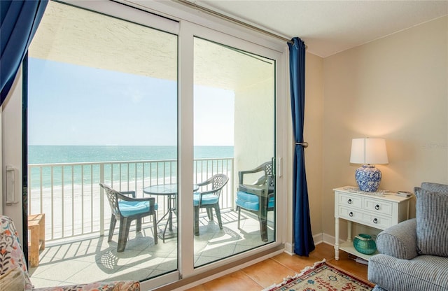 doorway to outside with a view of the beach, a water view, and baseboards