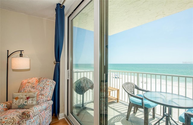 balcony featuring a view of the beach and a water view