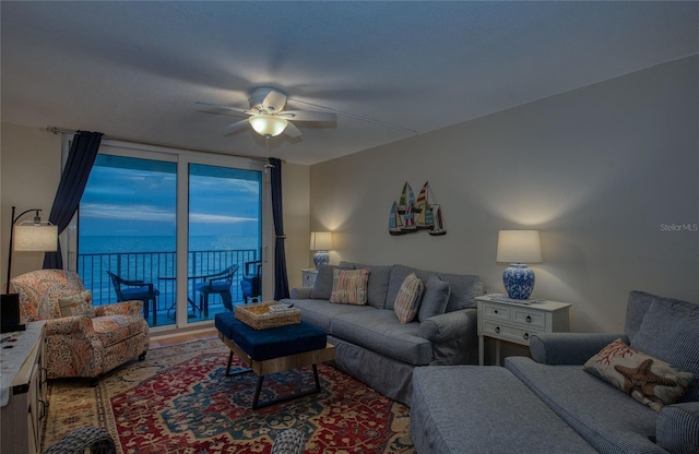 living room with a water view, ceiling fan, and floor to ceiling windows