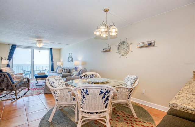 dining area featuring light tile patterned floors, baseboards, and ceiling fan with notable chandelier