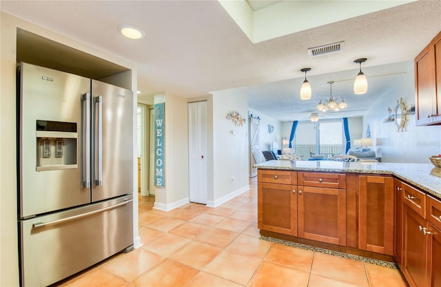 kitchen with a peninsula, brown cabinetry, stainless steel fridge with ice dispenser, visible vents, and light tile patterned flooring