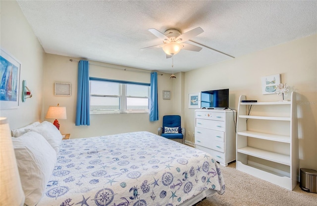 carpeted bedroom featuring ceiling fan and a textured ceiling