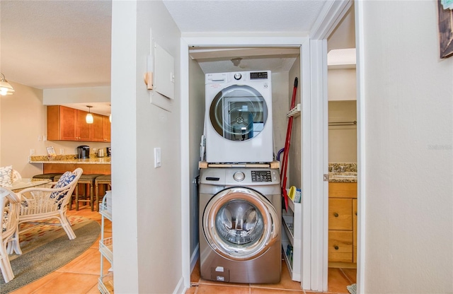 laundry area featuring stacked washer and clothes dryer, laundry area, and light tile patterned flooring
