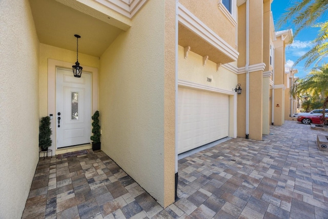 entrance to property with driveway, stucco siding, and a garage