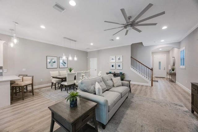 living area featuring stairs, crown molding, light wood finished floors, and visible vents