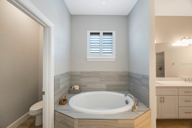 bathroom with toilet, a garden tub, and vanity