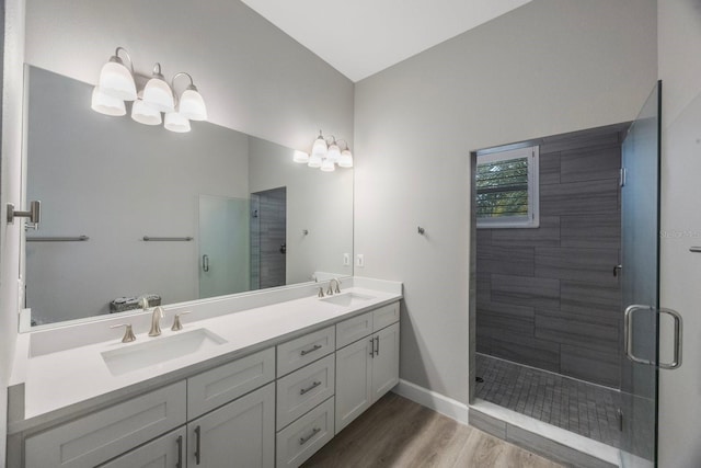 full bath with a sink, double vanity, a shower stall, and wood finished floors