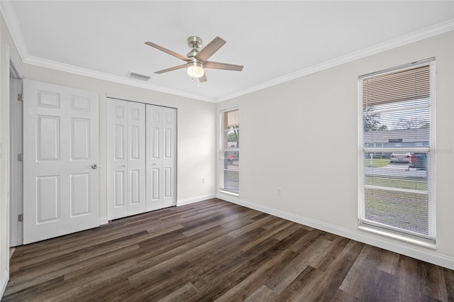unfurnished bedroom featuring a closet, crown molding, visible vents, baseboards, and dark wood-type flooring