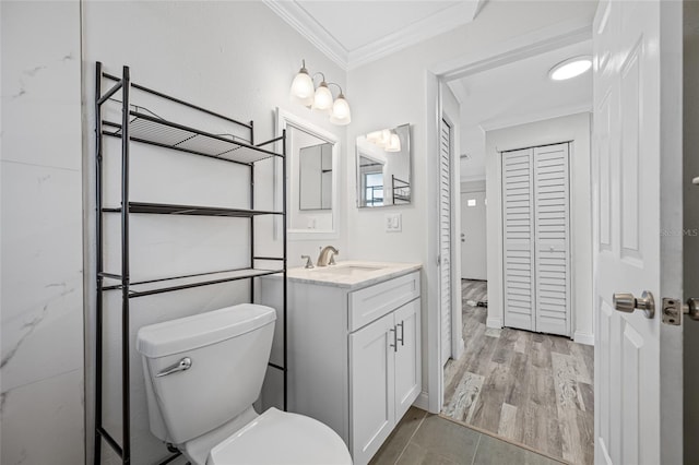 bathroom featuring a closet, toilet, vanity, and ornamental molding