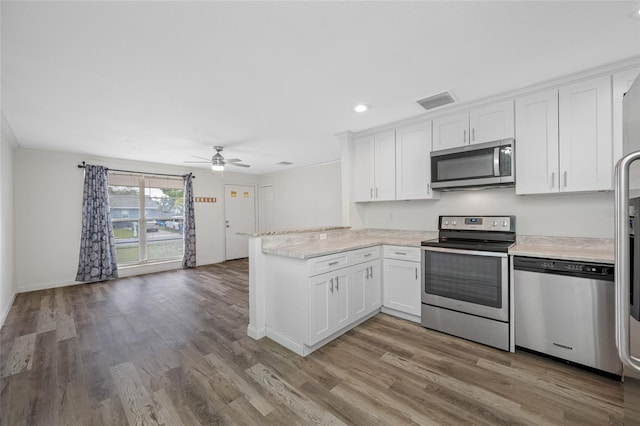 kitchen featuring a peninsula, appliances with stainless steel finishes, white cabinets, and light wood-type flooring