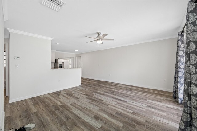 unfurnished living room with wood finished floors, a ceiling fan, crown molding, visible vents, and baseboards