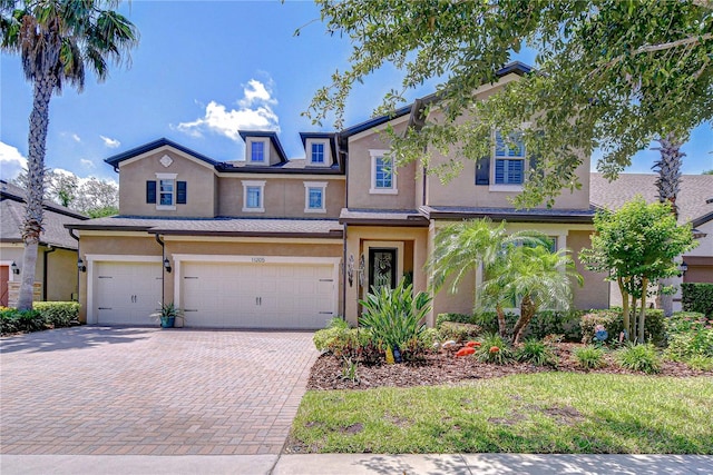 view of front of property with stucco siding, a garage, and decorative driveway