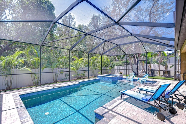 view of swimming pool featuring a fenced backyard, a patio, a pool with connected hot tub, and glass enclosure