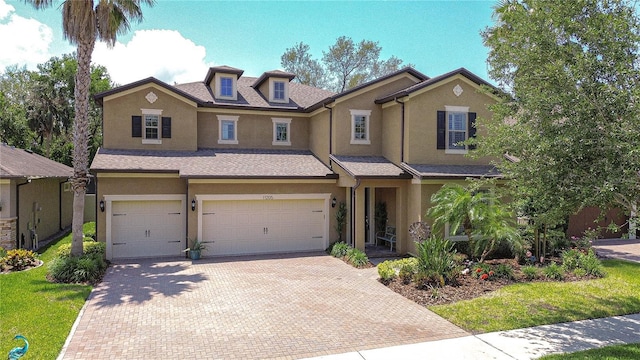 view of front of house with stucco siding, a garage, and decorative driveway