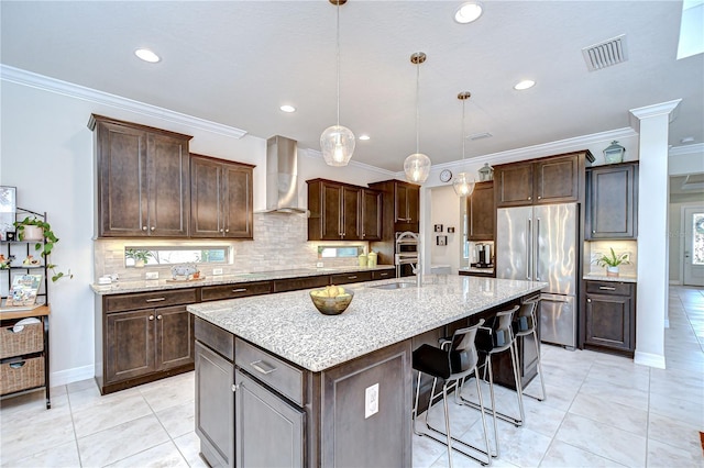 kitchen featuring wall chimney exhaust hood, appliances with stainless steel finishes, crown molding, a sink, and dark brown cabinets