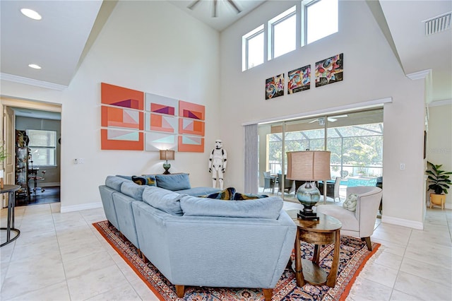 living area with ceiling fan, baseboards, a high ceiling, a sunroom, and ornamental molding