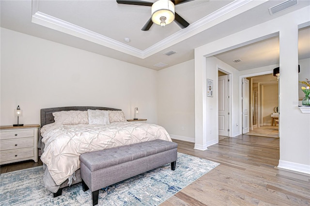 bedroom featuring crown molding, wood finished floors, baseboards, a raised ceiling, and ceiling fan