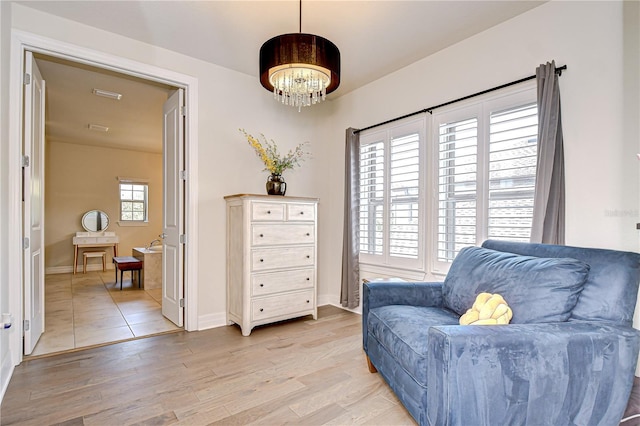 living area with a chandelier, light wood finished floors, and baseboards