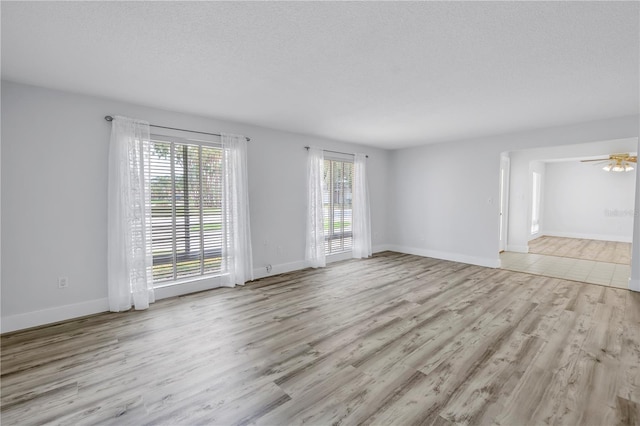 unfurnished living room with wood finished floors, baseboards, a textured ceiling, and a ceiling fan