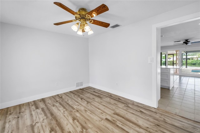 unfurnished room with ceiling fan, light wood-style flooring, and baseboards