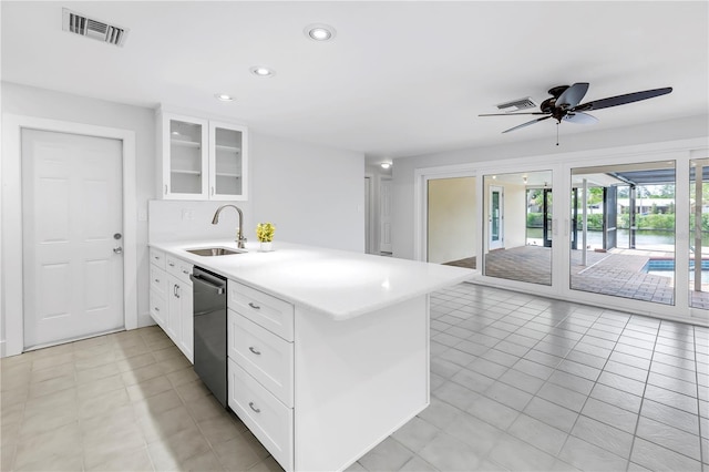 kitchen featuring dishwasher, a sink, a peninsula, light countertops, and glass insert cabinets