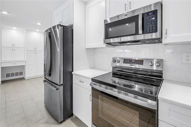 kitchen featuring appliances with stainless steel finishes, white cabinets, tasteful backsplash, recessed lighting, and light stone countertops