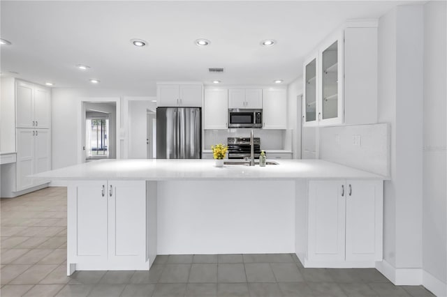 kitchen featuring stainless steel appliances, glass insert cabinets, a sink, white cabinetry, and recessed lighting