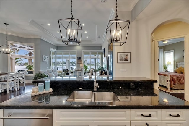 kitchen featuring a chandelier, a sink, open floor plan, arched walkways, and dark stone countertops