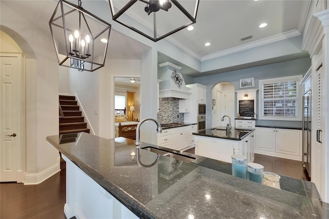 kitchen with a sink, appliances with stainless steel finishes, arched walkways, crown molding, and recessed lighting