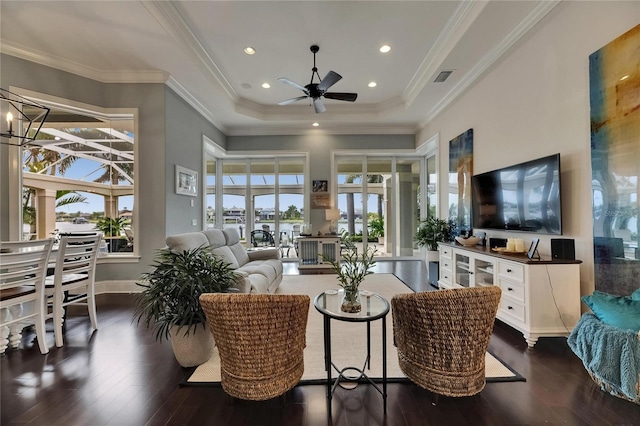living room with a ceiling fan, plenty of natural light, dark wood-style floors, a towering ceiling, and crown molding