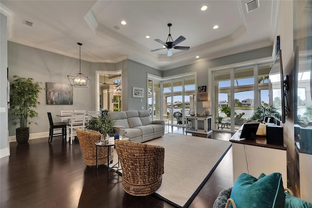 living area featuring a tray ceiling, a ceiling fan, dark wood finished floors, recessed lighting, and a chandelier