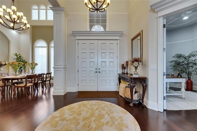 entrance foyer with a chandelier, dark wood-type flooring, healthy amount of natural light, and a high ceiling
