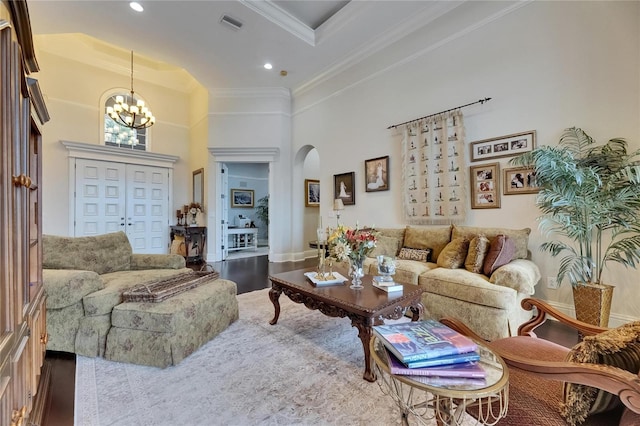 living room featuring arched walkways, crown molding, a towering ceiling, a chandelier, and recessed lighting