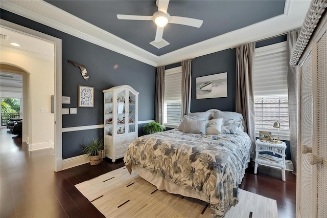 bedroom featuring arched walkways, wood finished floors, ornamental molding, baseboards, and ceiling fan