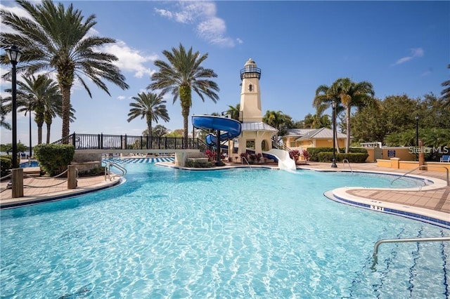 community pool featuring a water slide, fence, and a patio