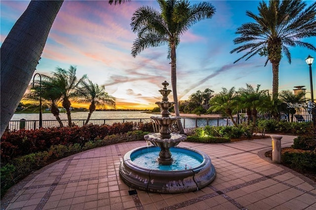 patio terrace at dusk featuring fence and a water view