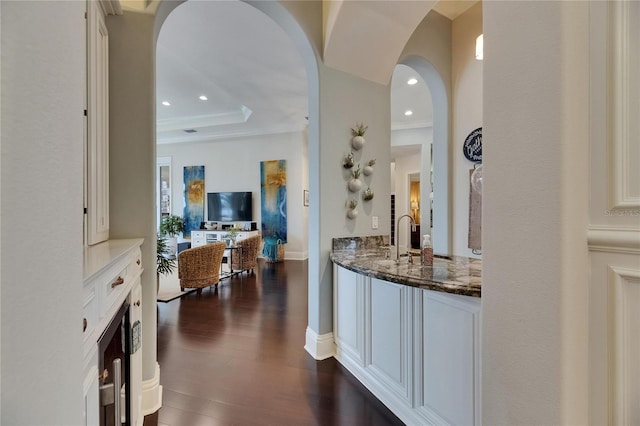bar with a sink, dark wood-style flooring, arched walkways, and recessed lighting