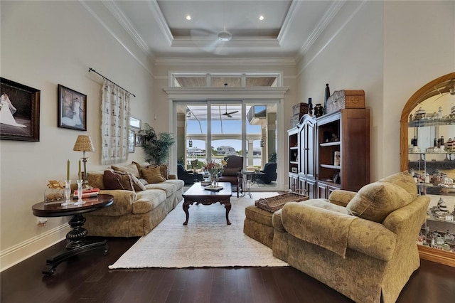 living room with ceiling fan, hardwood / wood-style floors, a raised ceiling, crown molding, and baseboards
