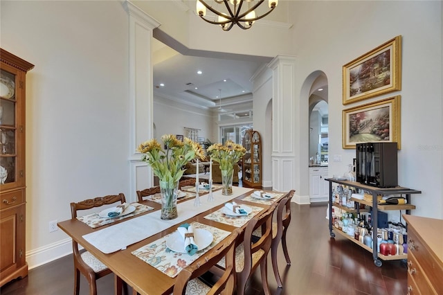 dining space with arched walkways, dark wood-style floors, ornamental molding, a chandelier, and baseboards