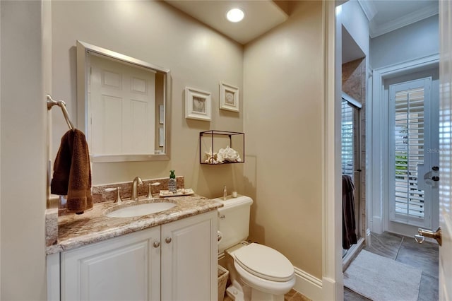 bathroom featuring a shower stall, vanity, ornamental molding, toilet, and baseboards