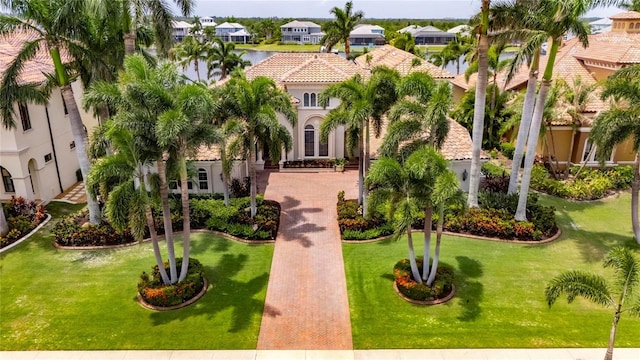 mediterranean / spanish-style home with stucco siding, a tiled roof, a water view, a front yard, and a residential view