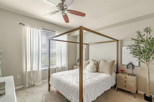bedroom featuring light carpet, multiple windows, baseboards, and a textured wall