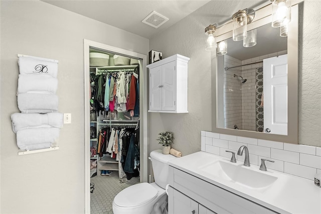 bathroom featuring a spacious closet, vanity, a shower, and toilet