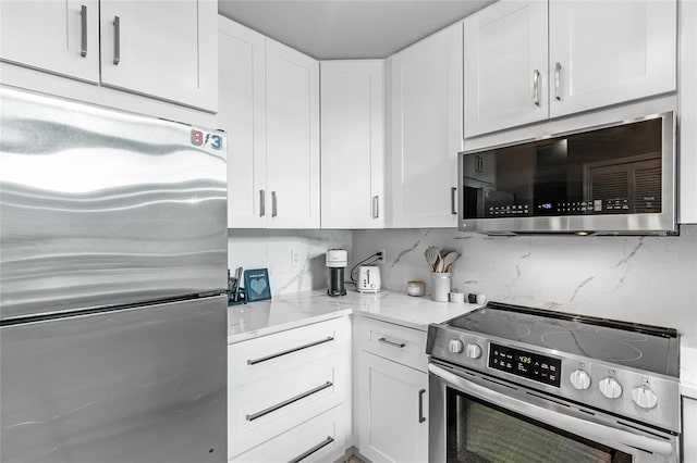 kitchen with stainless steel appliances, white cabinets, backsplash, and light stone counters