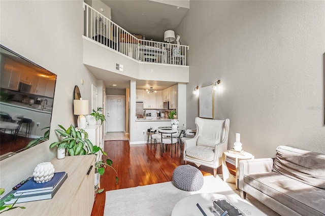 living room featuring wood finished floors, a high ceiling, and baseboards