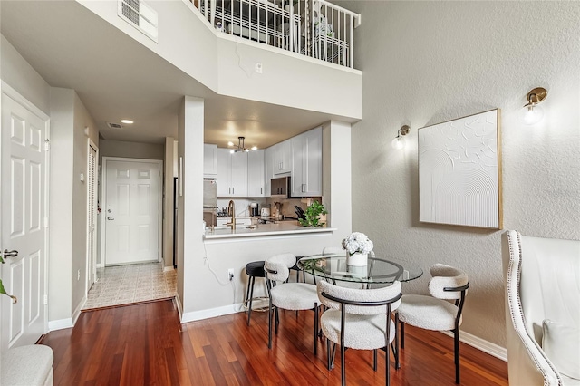 dining room with wood finished floors, a textured wall, baseboards, and a chandelier