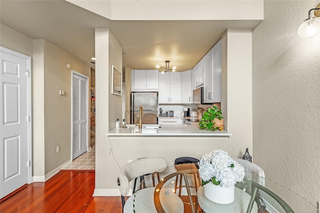 kitchen with stainless steel appliances, wood finished floors, light countertops, a sink, and a textured wall